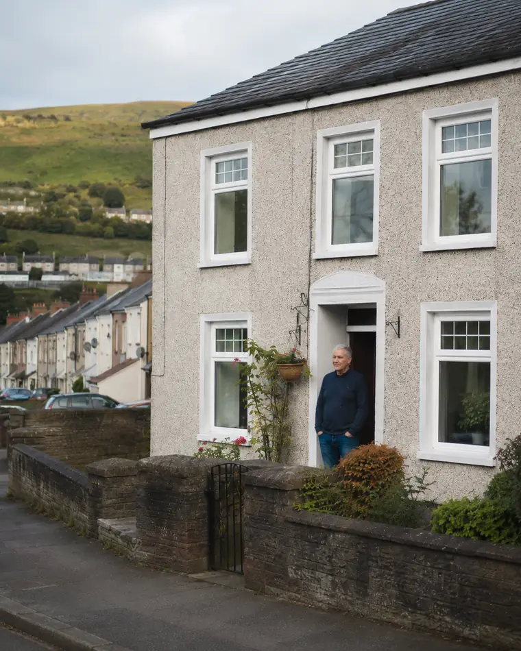 Welsh homeowner outside their valley home fitted with new white uPVC double glazing